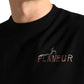 Close-up of a person wearing the FLANEUR Passage of Time T-Shirt in black, featuring "FLÂNEUR" and an abstract chest embroidery.