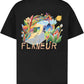 The FLANEUR Passage of Time T-Shirt in black features a colorful surreal landscape with plants, house, and "FLÂNEUR" below the artwork—a bold graphic tee for any collection.
