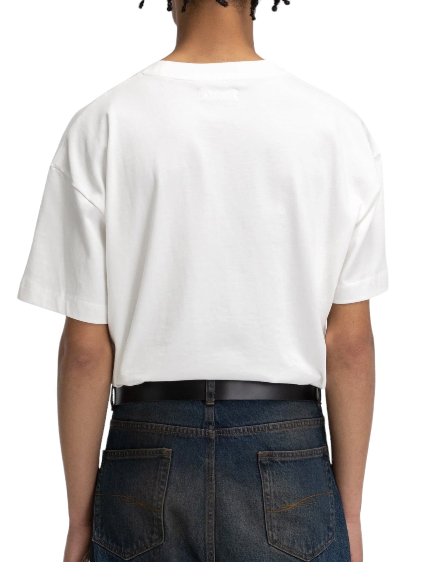 The image depicts the back of a person wearing the Flaneur Printed Logo T-Shirt in white paired with dark jeans.