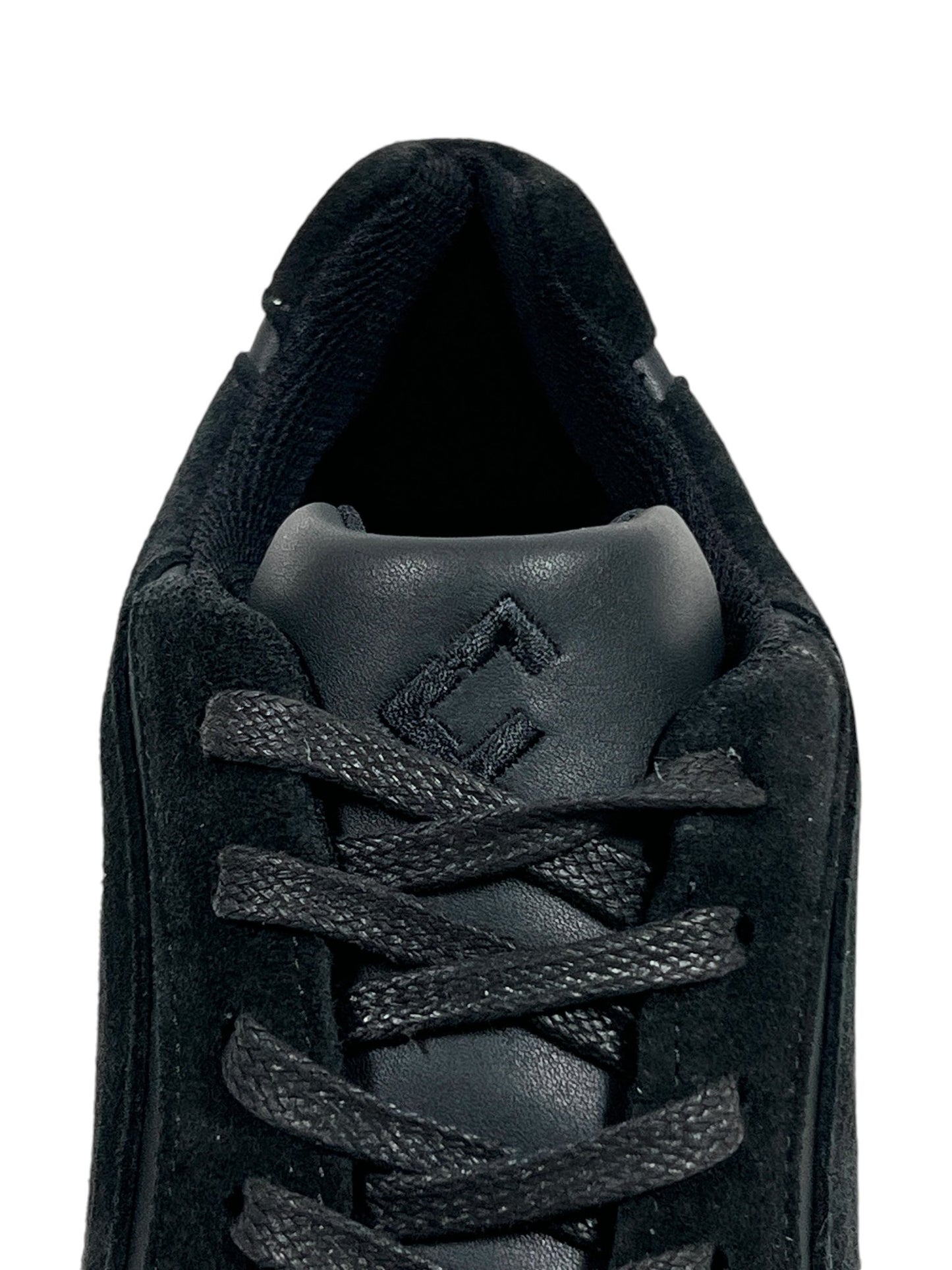 Close-up view of a FLANEUR TIVOLI RUNNER BLACK sneaker, highlighting the top lacing area and padded tongue. The shoe features black laces, a subtle "FLANEUR" logo on the tongue, and is crafted from premium calfskin leather.