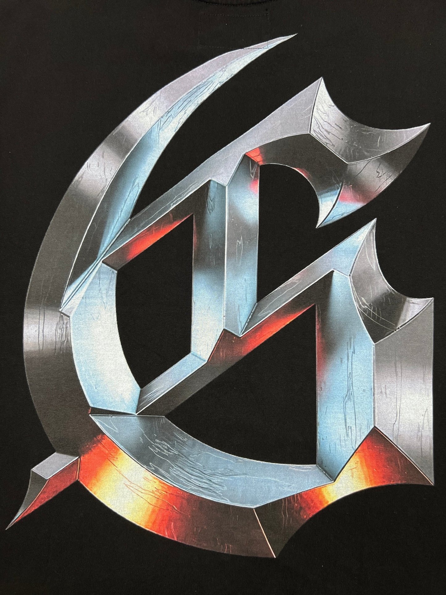 A metallic 3D "G" with sharp edges and reflective surfaces stands out on a black background, echoing the GODSPEED brand's New Age style on the Godspeed New Age Logo T-Shirt Black—ideal for fans of striking, Godspeed-inspired design.