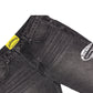 A pair of GODSPEED OG Logo Flared Denim Grey Wash jeans featuring front pockets, a visible yellow waistband label, and a white graphic detail on the thigh.