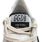 Close-up of a Golden Goose GMF00117 Ball Star sneaker tongue displaying "GGDB" and "Made in Italy." Partially visible white laces complement the design, with hints of a rubber sole peeking through.