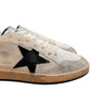 The Golden Goose GMF00117 Ball Star sneakers feature a black leather star design on white and beige with textured sides and slightly worn rubber soles, by GOLDEN GOOSE.