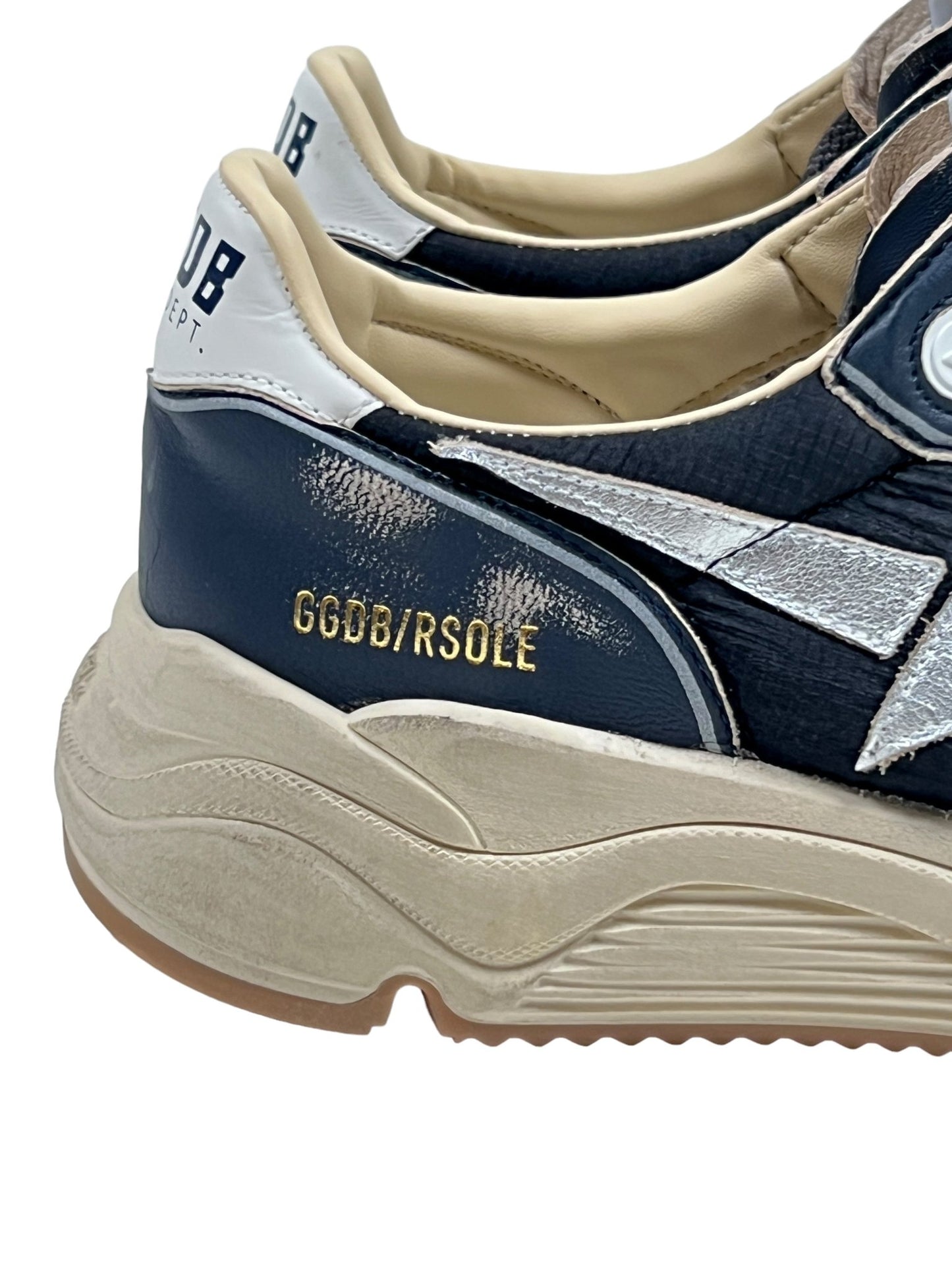 Close-up of two black sneakers with white accents, featuring the branding "GGDB/RSOLE" in gold letters on the side and visible wear on the midsole area. These Golden Goose GMF00126 Running Sole sneakers in dark blue, black, silver, and white showcase both style and comfort.