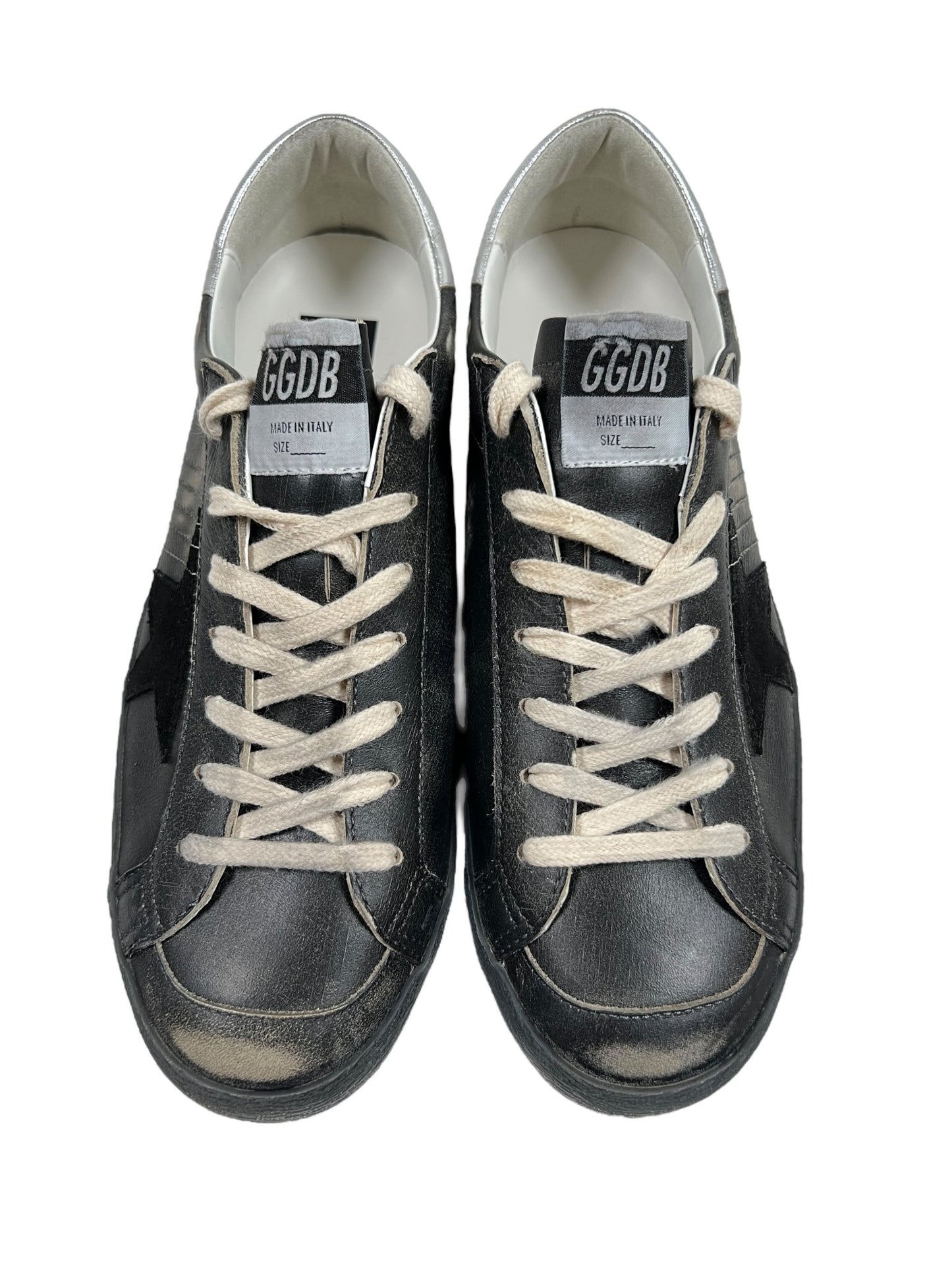 A pair of GOLDEN GOOSE GMF00290 SUPER STAR LEATHER BLACK SILVER sneakers with white laces, labeled GGDB and made in Italy by GOLDEN GOOSE.