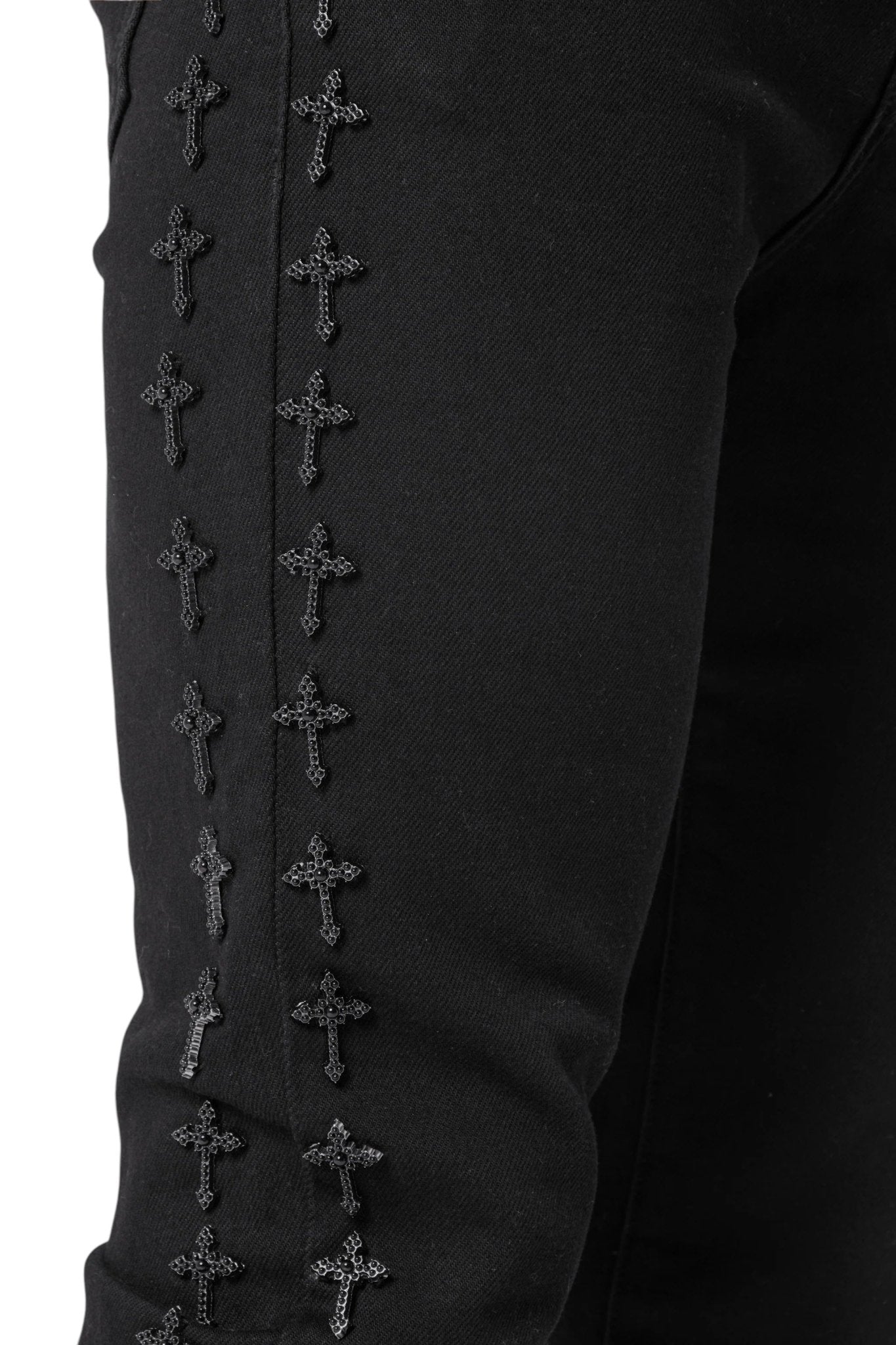 The Guapi All Black Crosses Embellished Denim from GUAPI features a streetwear aesthetic with embroidered crosses along the seam.