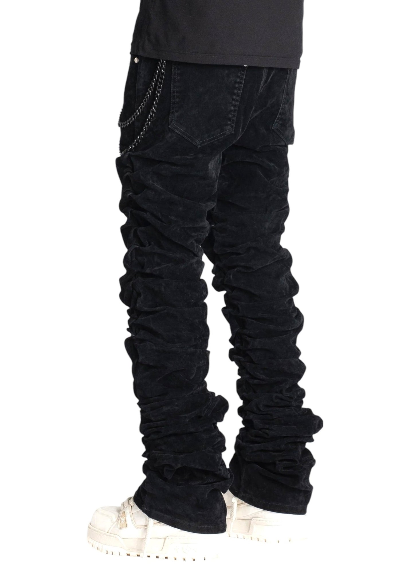 A person wearing Guapi All Black Super Stacked Denim V2 with a chain and white sneakers, featuring a tapered fit, stands against a plain white background.