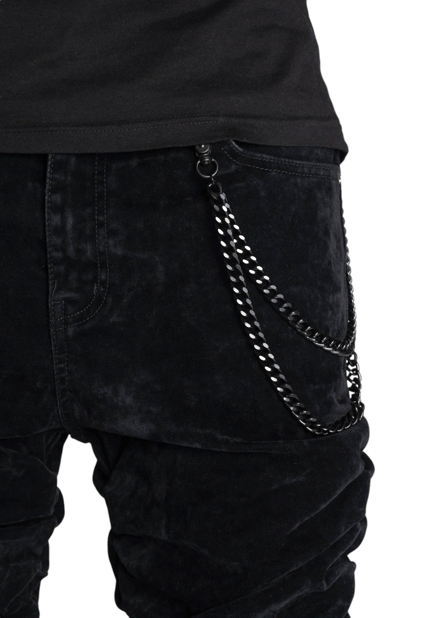 A person is seen wearing the Guapi All Black Super Stacked Denim V2 from GUAPI, featuring a tapered fit elegantly adorned with a silver chain accessory on the pocket.