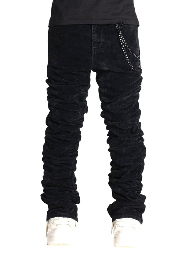 A person wearing the GUAPI All Black Super Stacked Denim V2 with a sleek chain detail showcases a tapered fit, complemented by stylish white shoes.