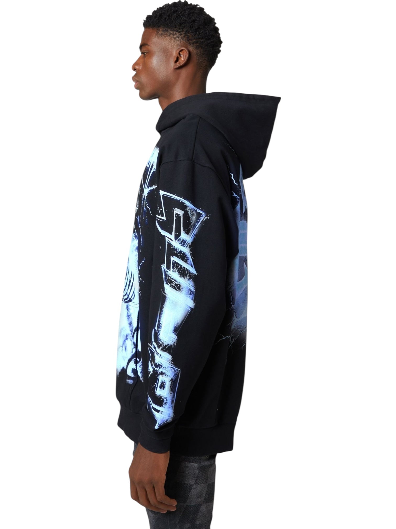 A person stands in profile wearing the GUAPI Black Revived Hoodie V2, a streetwear piece featuring striking blue and white graphic designs on the sleeves and back.