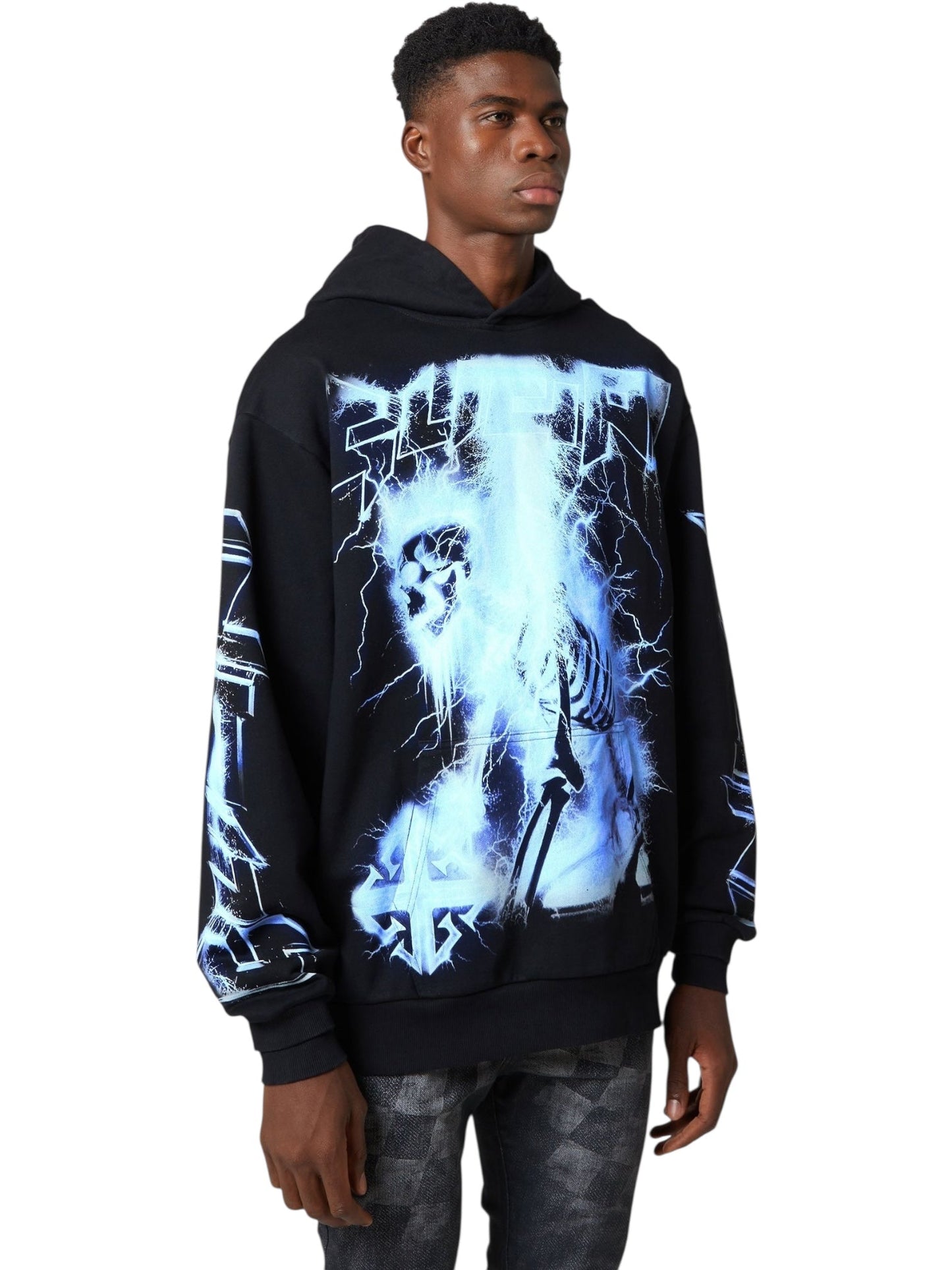 A man stands against a plain background, wearing the GUAPI Black Revived Hoodie V2 with blue and white skeleton and lightning graphics, paired with dark patterned pants—showcasing bold GUAPI streetwear style.