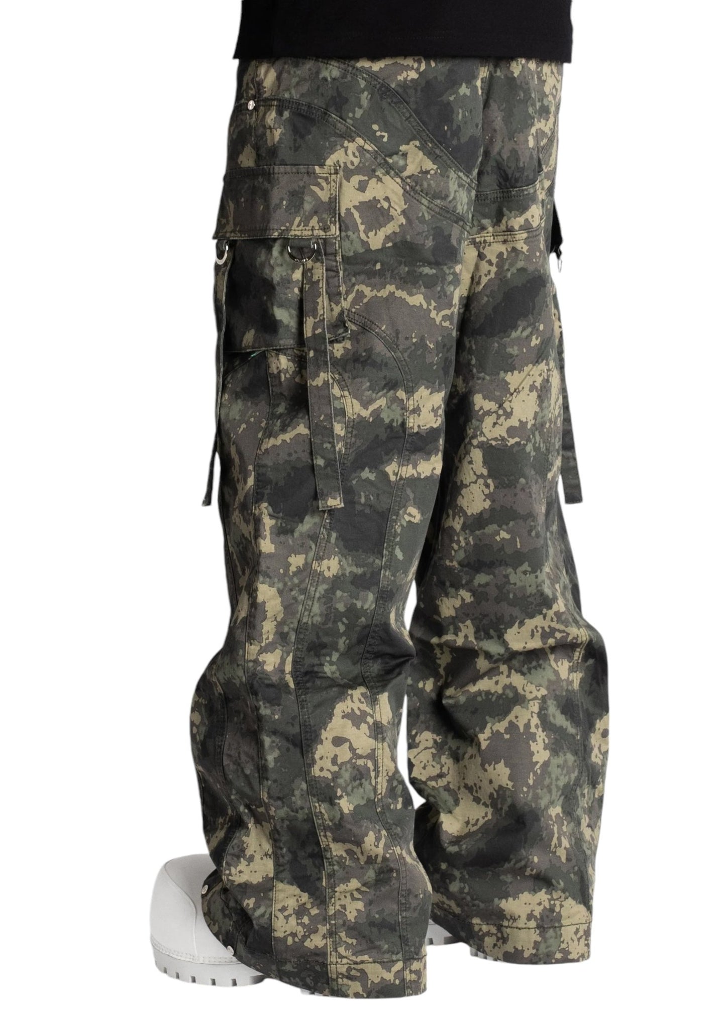 A person sporting the Guapi Camo Extra Baggy Cargos V3 by GUAPI paired with sleek white shoes, perfectly embodying trendy streetwear, as seen from the side.