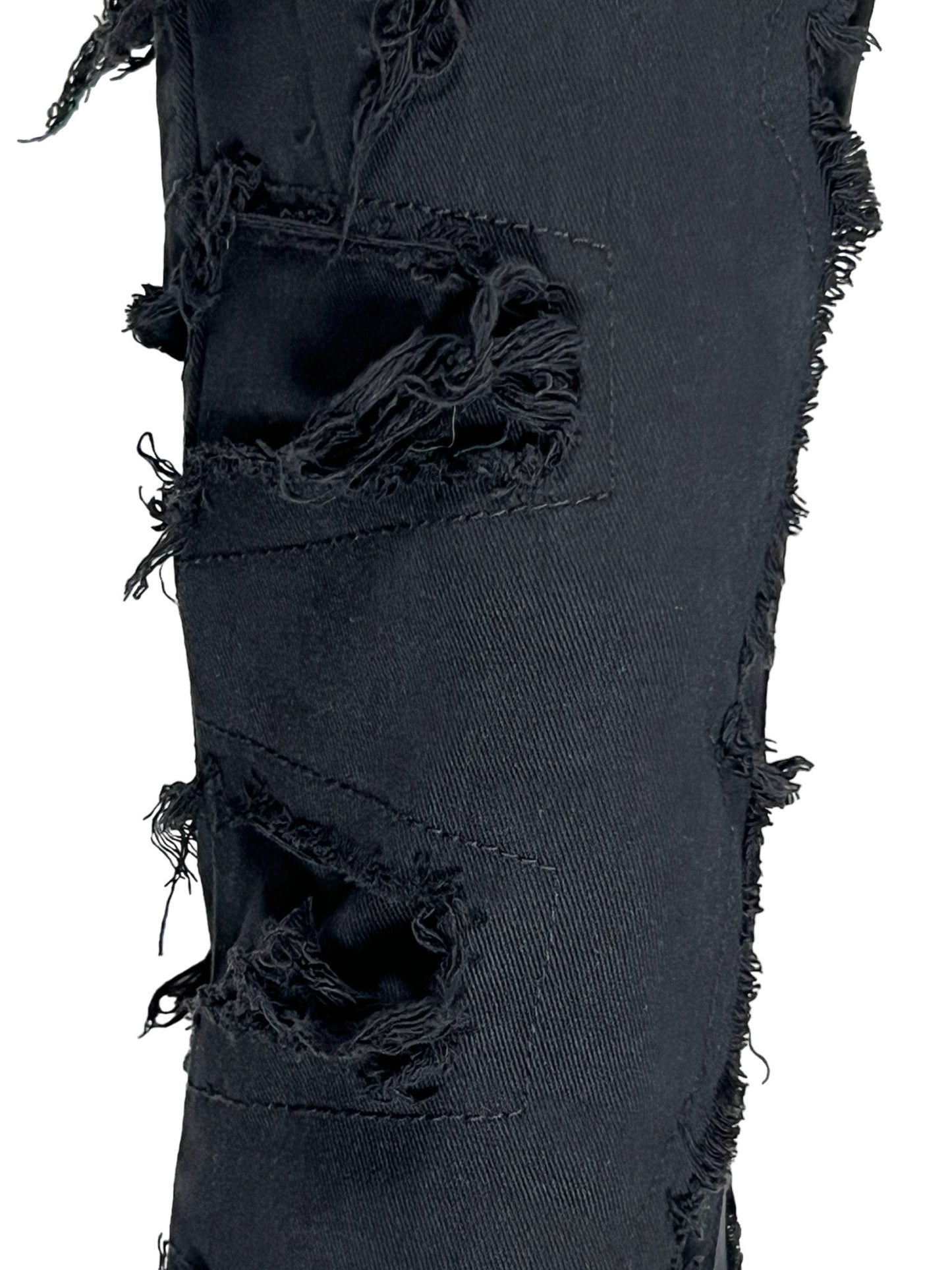 Close-up of a luxury GUAPI black distressed denim with multiple frayed holes.
