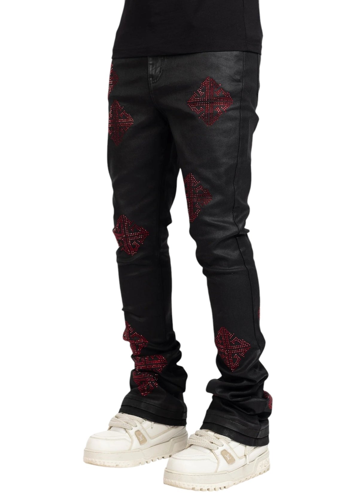 The person is wearing GUAPI's limited edition Obsidian Black Icon Embellished Denim V2 with red diamond accents, paired with white sneakers, against a plain background.
