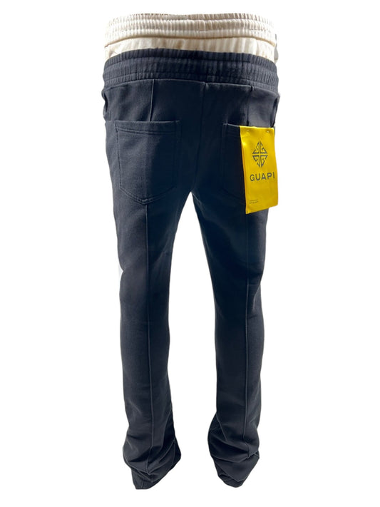 The Guapi Obsidian Black Sweat Pants by GUAPI feature a double waist, rear pockets, and a yellow GUAP label on the right pocket. Made from 100% cotton, they ensure ultimate comfort and style.