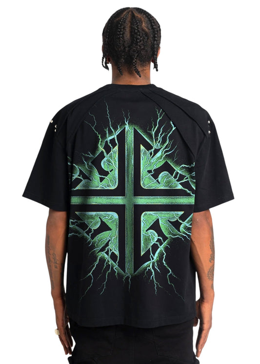 A person with braided hair is wearing a GUAPI oversized streetwear T-shirt known as the Guapi Obsidian Blk Electroshock Therapy Tee, crafted from premium cotton and featuring a striking green cracked cross design on the back.