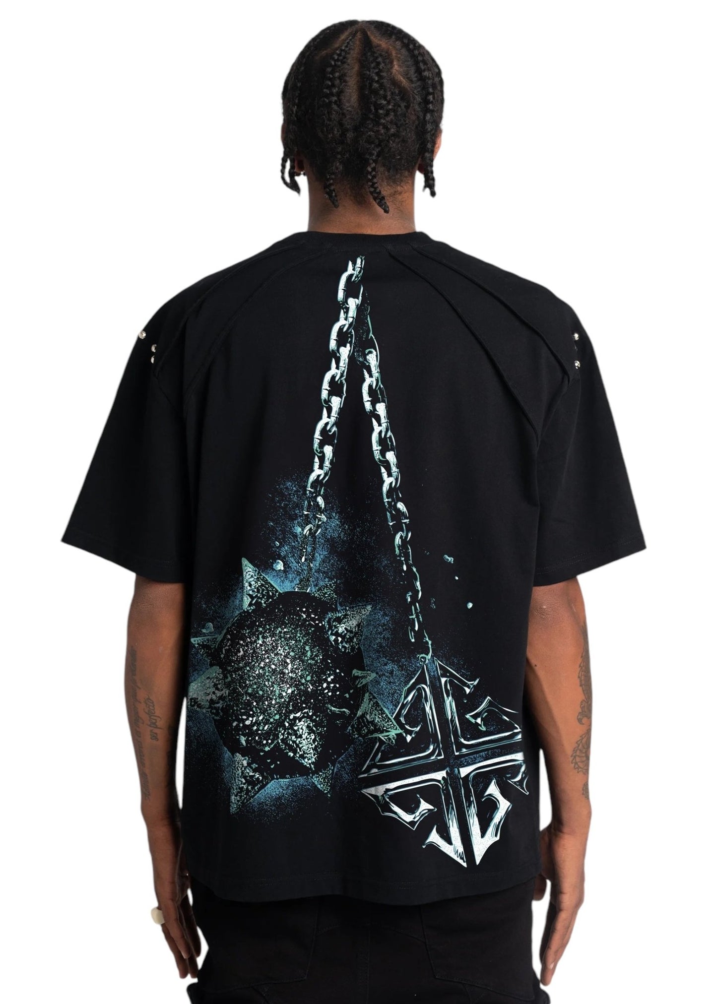 Wearing the Guapi skull cracker tee in black from GUAPI, a person stands against a plain background, featuring a bold design of a skull cracker mace and chain on the back.