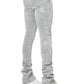 Someone wearing GUAPI's Guapi Smoke Grey Distressed Cross Denim, featuring rhinestone cross details, pairs the light gray jeans with chunky white sneakers; outfit is shown from the back and side.