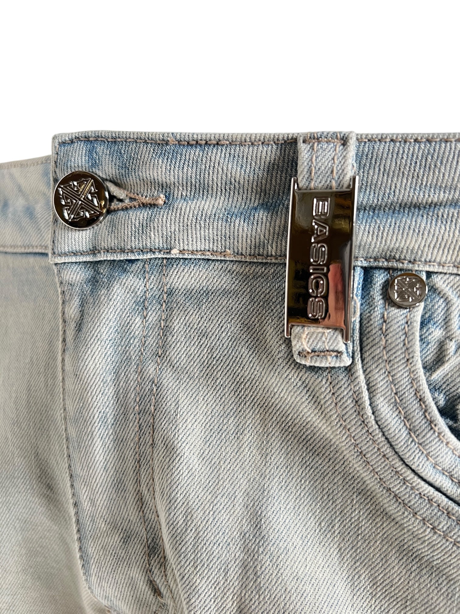 Close-up of GUAPI's Guapi Vintage Blue Basics Regular Denim V2 jeans featuring a metal "Basics" tag above the pocket and a star-embossed button at the waistband.