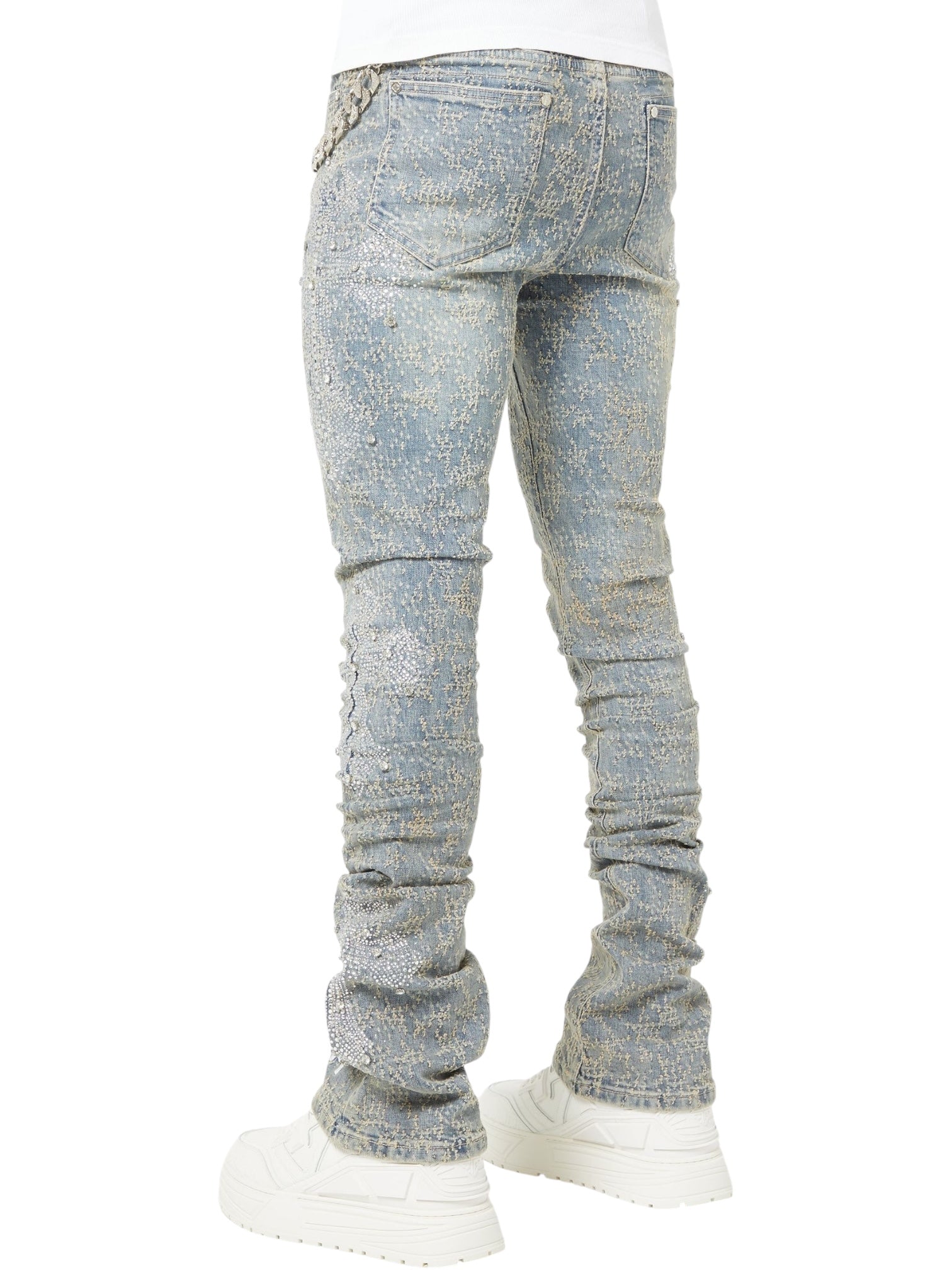 A person wearing GUAPI Vintage Blue Distressed Cross Denim jeans with a slim fit, light blue hue, and white chunky sneakers, photographed from the back.