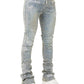 Model wearing GUAPI Vintage Blue Distressed Cross Denim jeans with visible "GUAPI" branding and white sneakers, shown from the waist down against a white background.