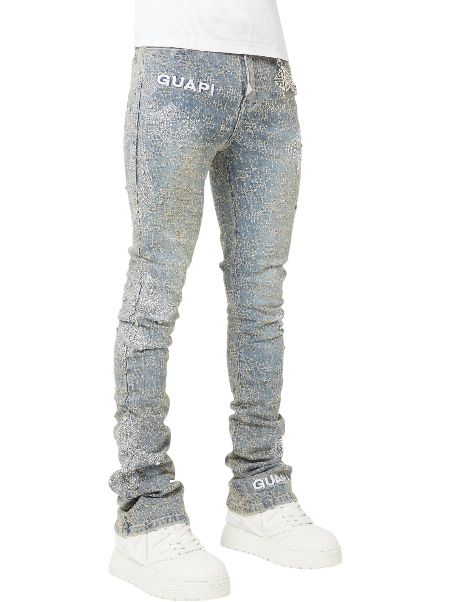Model wearing GUAPI Vintage Blue Distressed Cross Denim jeans with visible "GUAPI" branding and white sneakers, shown from the waist down against a white background.