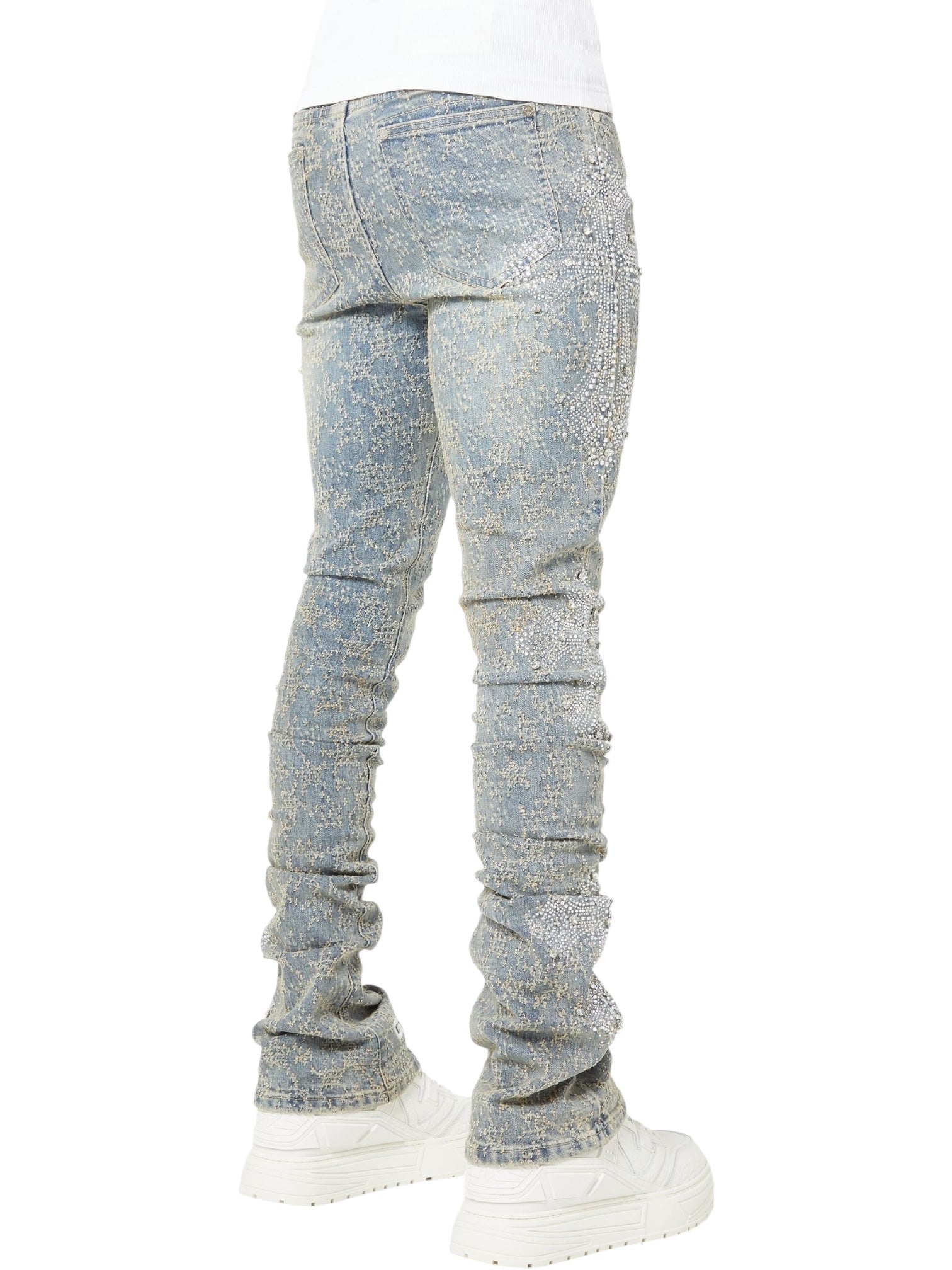 Photographed from the back, a person wears GUAPI's Guapi Vintage Blue Distressed Cross Denim jeans paired with white platform sneakers.