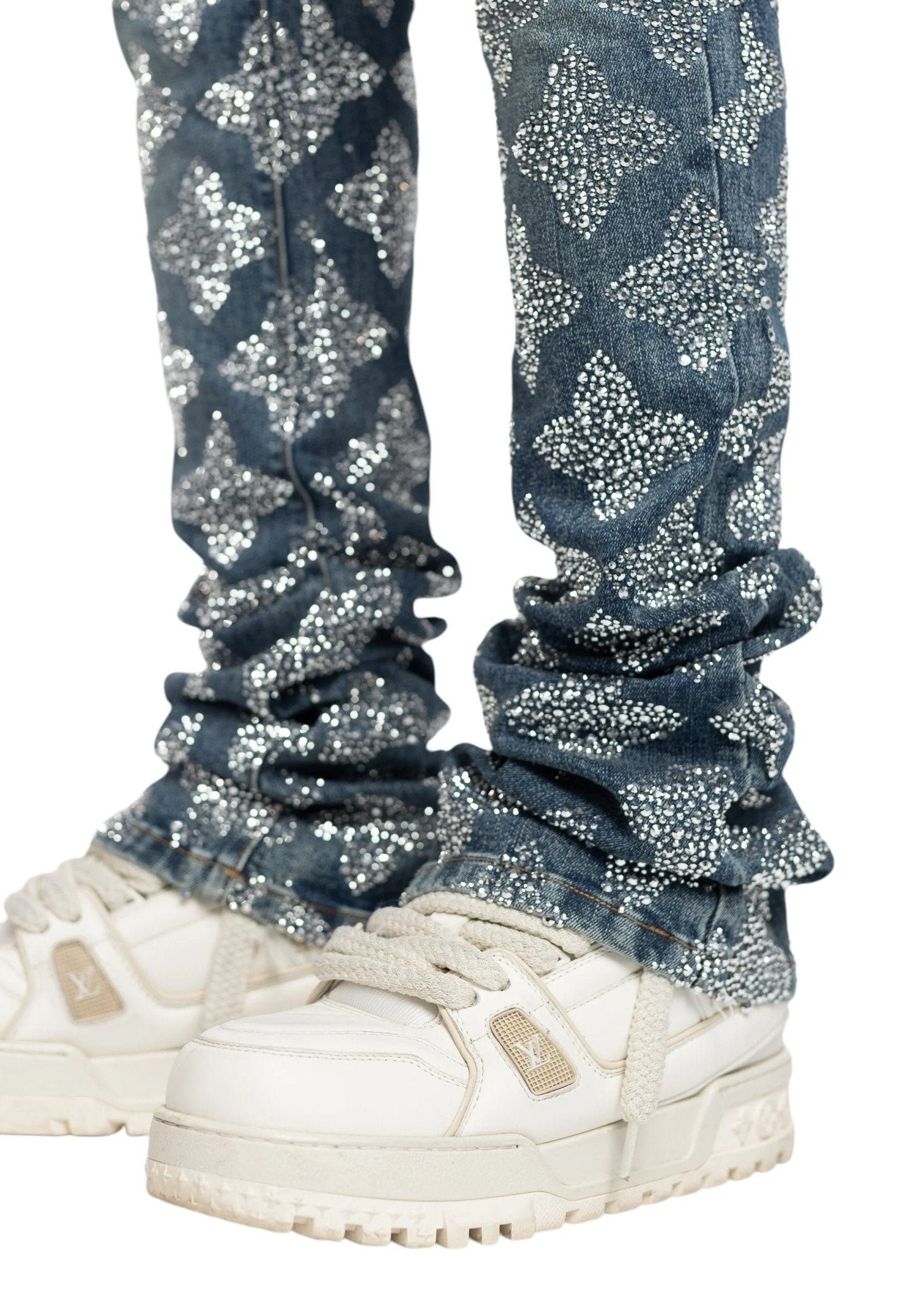 A person is wearing white sneakers and slim-fit Guapi Vintage Blue Embellished Denim by GUAPI, featuring a sparkling floral pattern design.