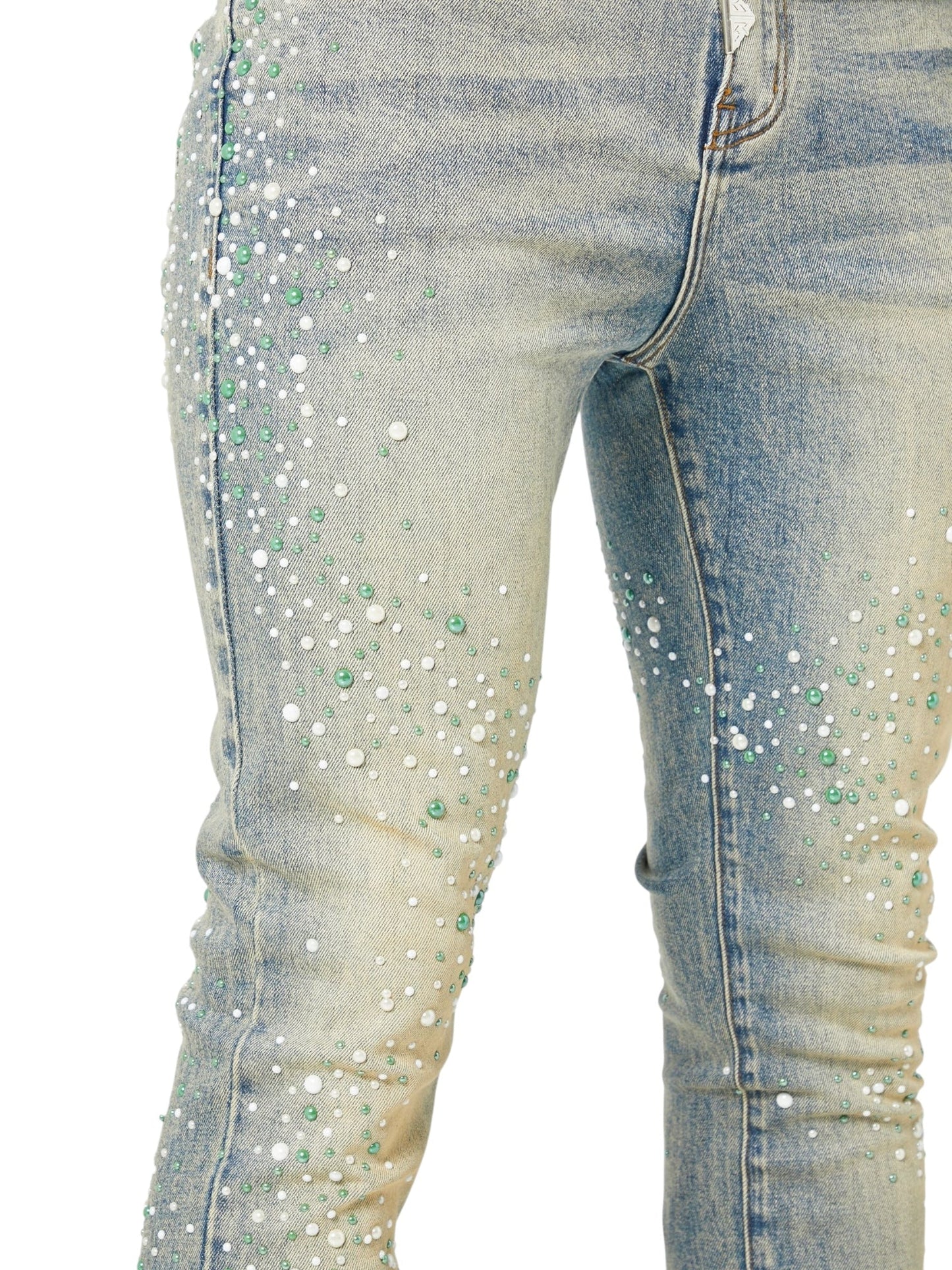 Close-up of GUAPI Guapi Vintage Olive Pearls Denim skinny jeans, featuring white and green beads arranged in a scattered pattern on the front and sides.