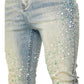 Close-up of GUAPI's Guapi Vintage Olive Pearls Denim skinny stacked jeans, detailed with scattered white and green bead embellishments on the front thigh and knee areas.
