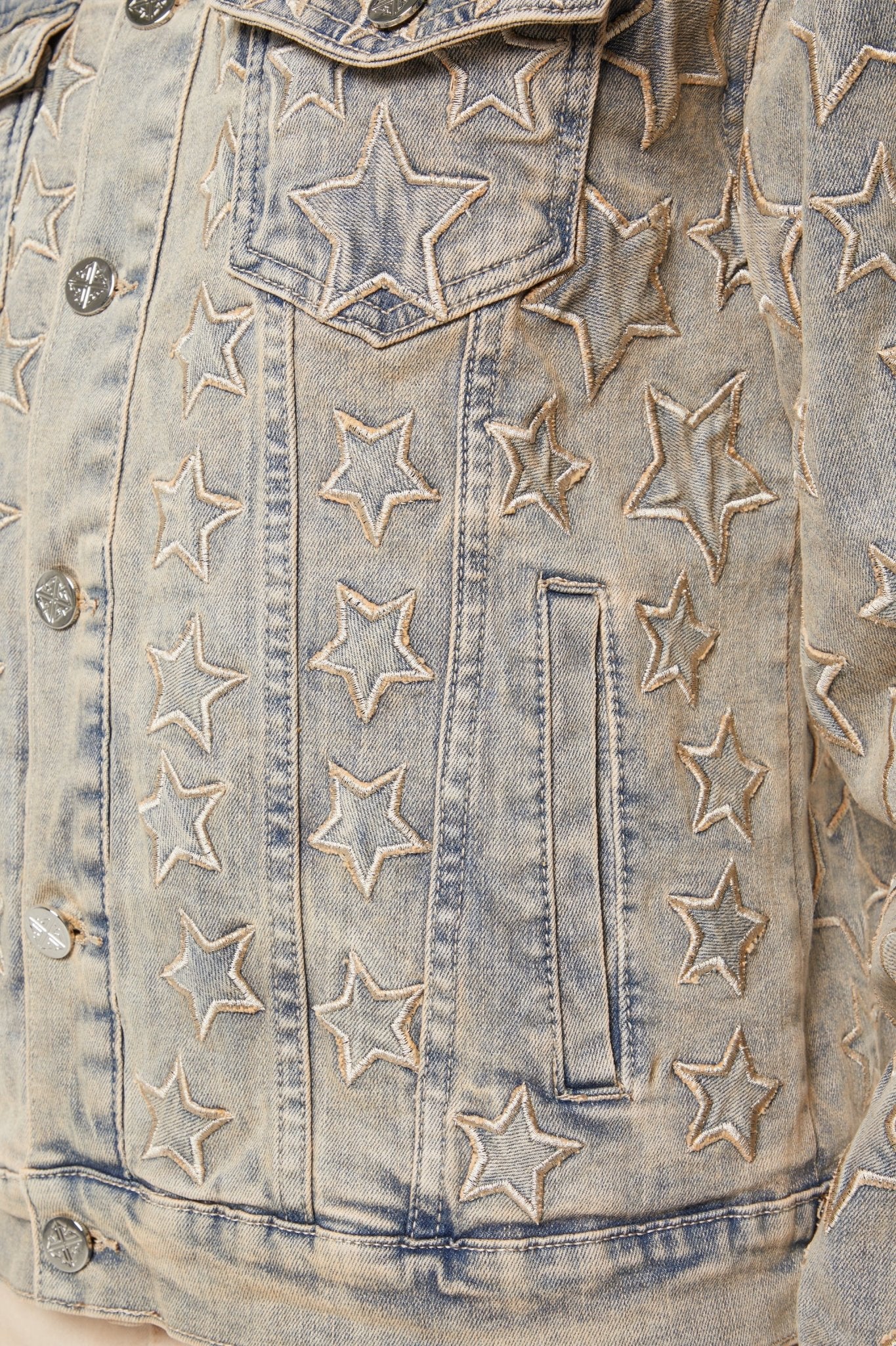 The Guapi Vintage Stars Denim Jacket by GUAPI showcases a vintage-wash denim adorned with exquisite star-shaped embroidery on the front and pocket, offering a timeless blend of classic style and modern flair.