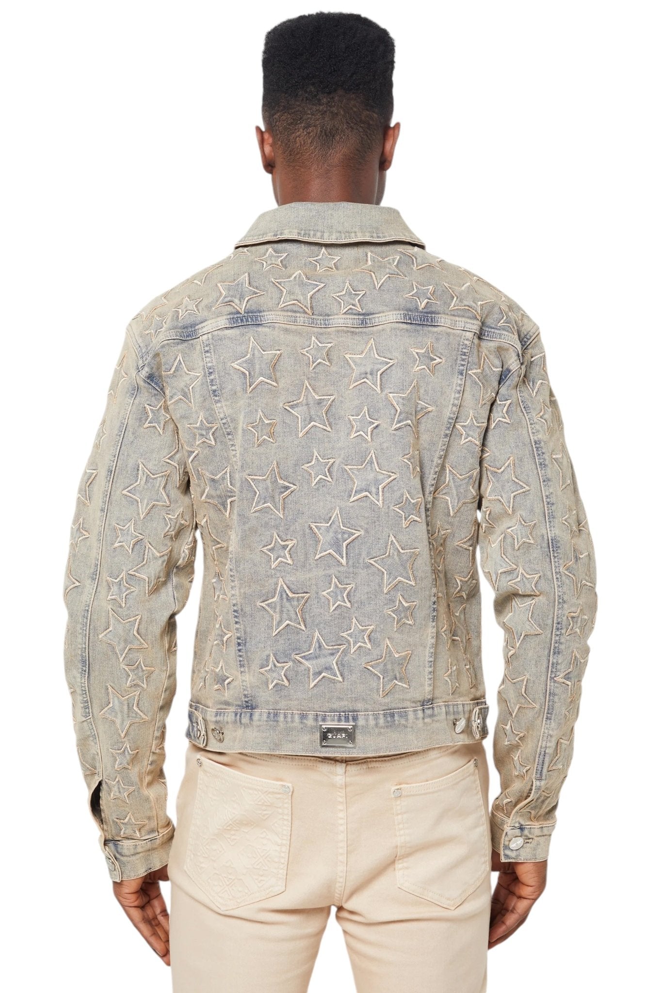 A rear view of a person sporting the Guapi Vintage Stars Denim Jacket by GUAPI paired with beige pants.