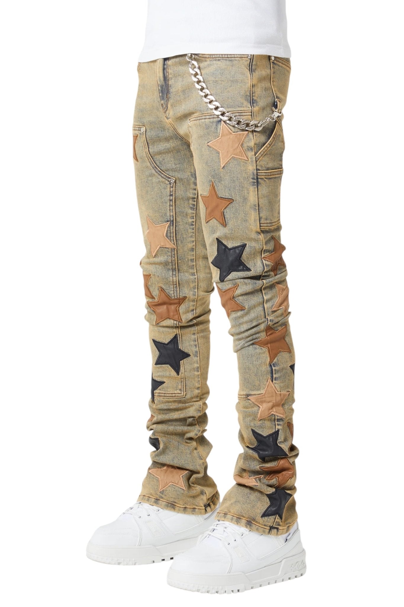 A person sporting the GUAPI Vintage Stars Denim V2 featuring a slim fit and stacked hem, paired with a chain and white sneakers.