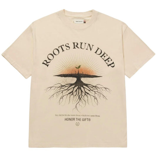 Introducing the Honor The Gift A-Spring Roots Run Deep Ss Tee in Bone from HONOR THE GIFT. This beige jersey t-shirt showcases the phrase "Roots Run Deep" along with a screen-printed tree graphic complete with roots. Below, it features the sentiment "We honor the roots from which we came from - Honor the Gift." Crafted from 100% cotton, this t-shirt offers ultimate comfort.