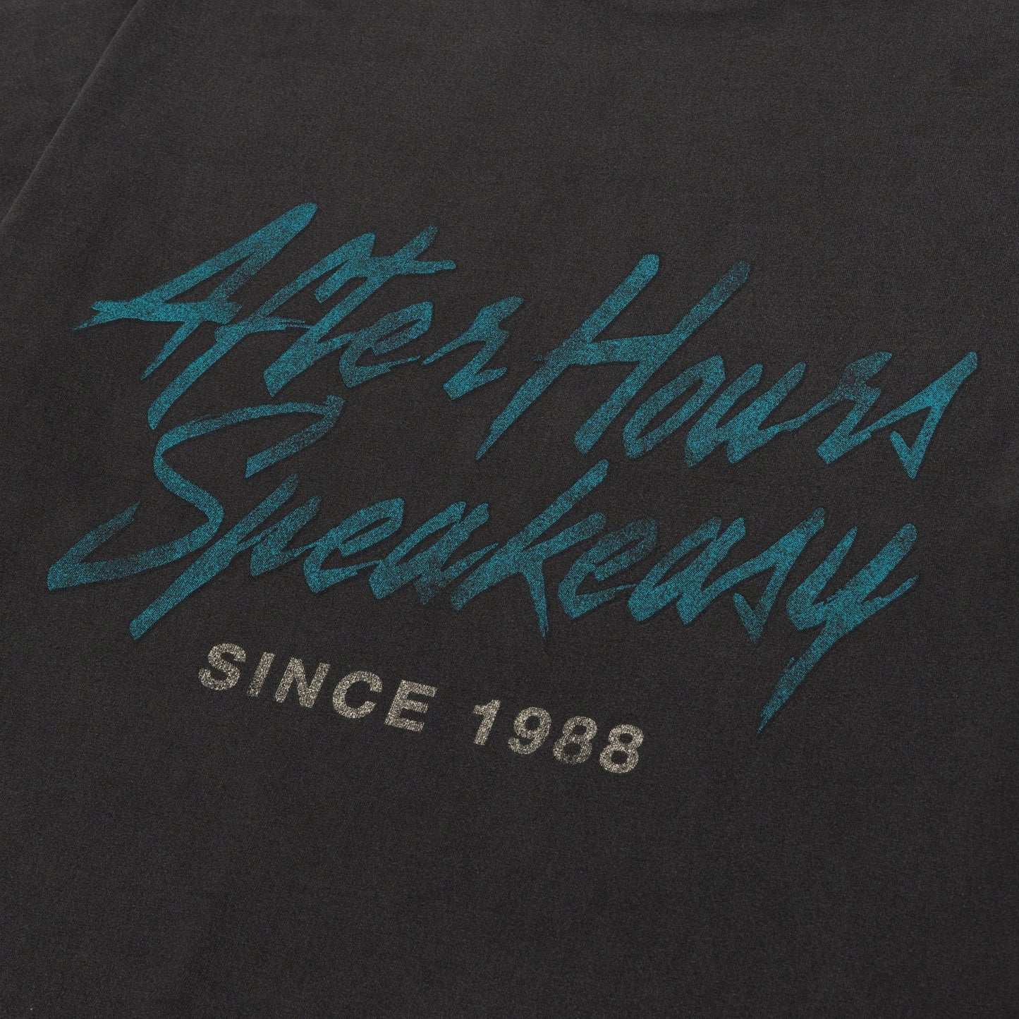 Close-up of the Honor The Gift After Hours T-shirt in black, featuring teal "After Hours Speakeasy" text and gray "Since 1988," evoking a vintage print. Brand: HONOR THE GIFT.