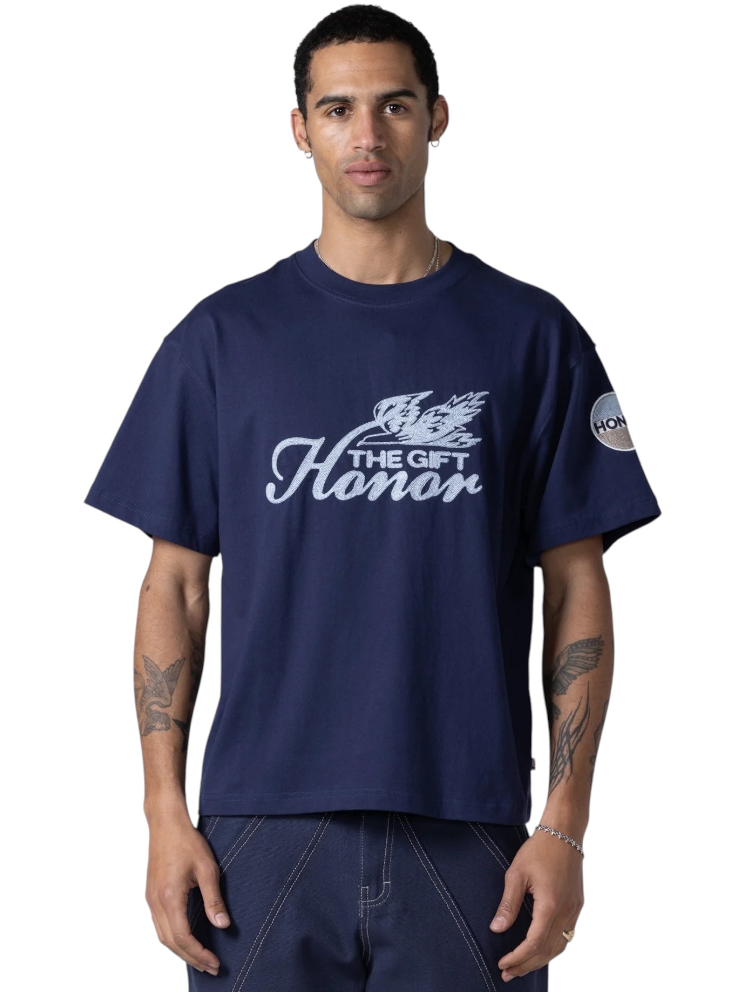 A man wears the HONOR THE GIFT Auto Club Box Tee Navy, a standard fit 100% cotton t-shirt featuring "The Gift Honor" with front graphic and "Honor" chain stitch embroidery on the left sleeve.