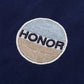 The "Honor The Gift Auto Club Box Tee Navy" by HONOR THE GIFT features a circular chain-stitched embroidered patch with "HONOR" on navy fabric, accented by light blue and beige segments.
