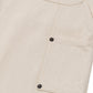 Close-up of the HONOR THE GIFT Gears Carpenter Short Cream, highlighting its textured 100% cotton twill fabric and a rectangular pocket with two black metal rivets and visible stitching.