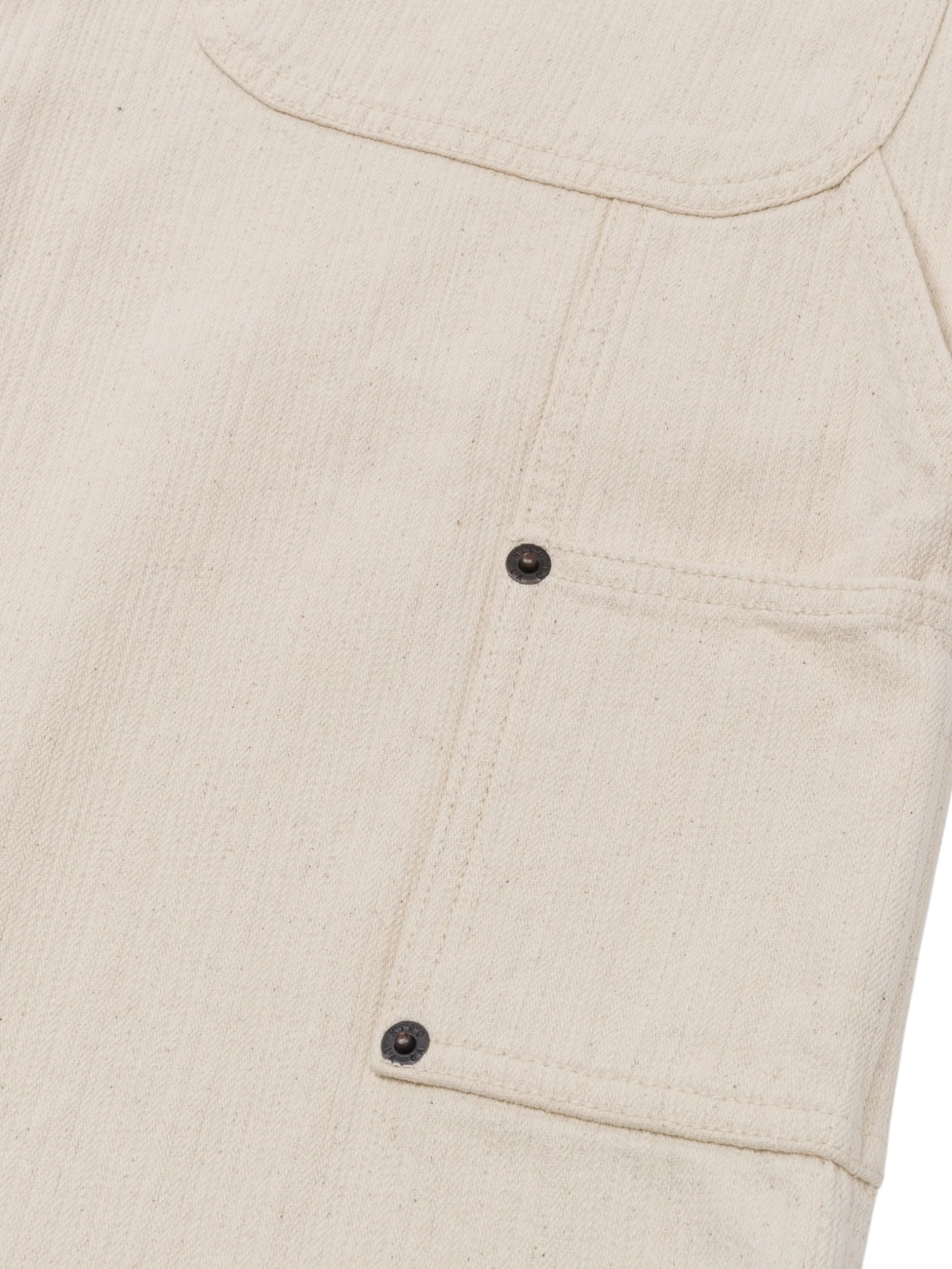 Close-up of the HONOR THE GIFT Gears Carpenter Short Cream, highlighting its textured 100% cotton twill fabric and a rectangular pocket with two black metal rivets and visible stitching.