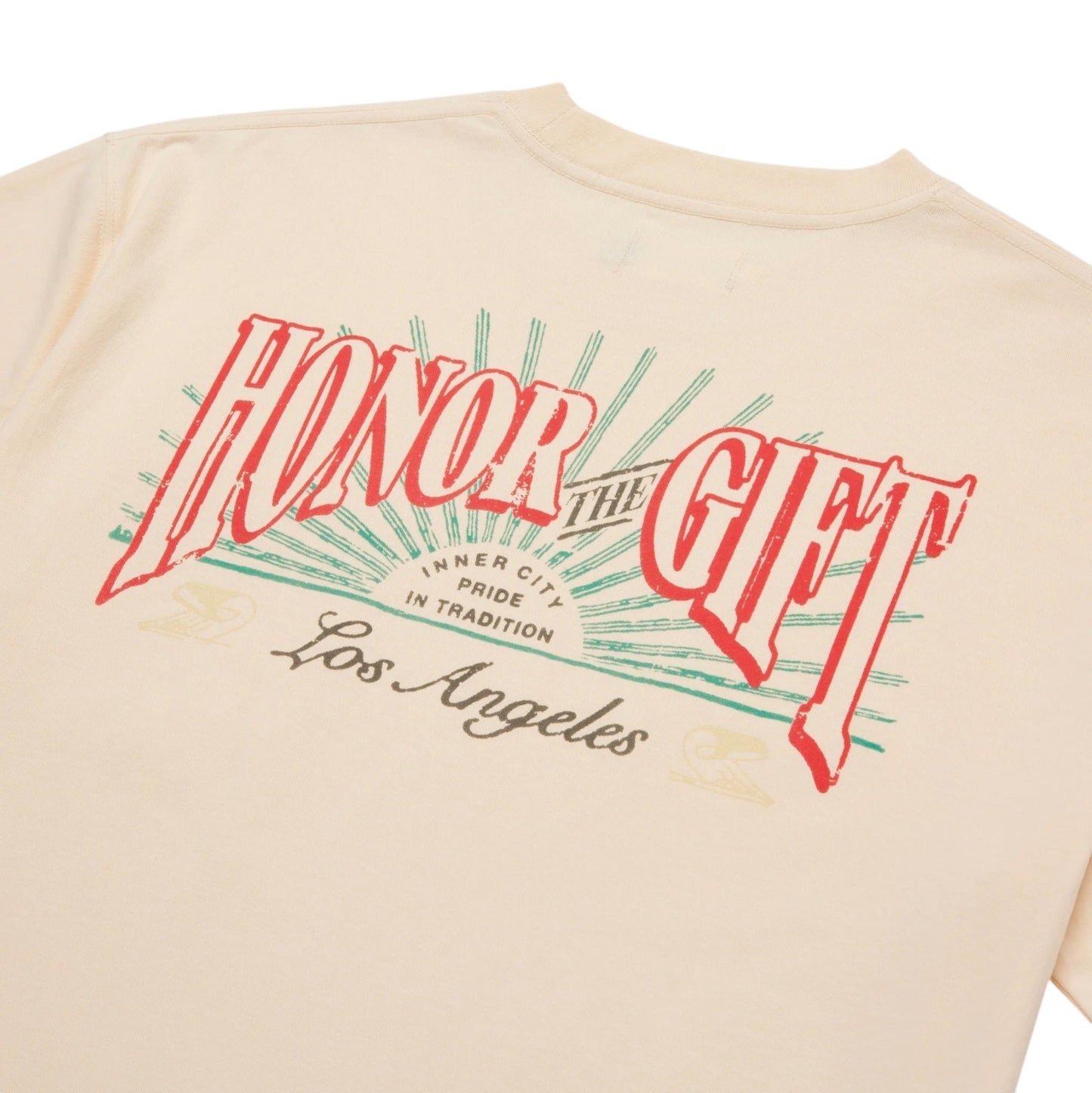 The Honor The Gift HTG Cigar Label SS Tee in Bone is a vintage-style T-shirt made from 100% cotton, showcasing a cream backdrop with "HONOR THE GIFT" boldly displayed in red letters, encircled by green rays that echo the style of a traditional cigar label. Below this design, it gracefully includes the phrase "Inner City Pride In Tradition Los Angeles" in script font.