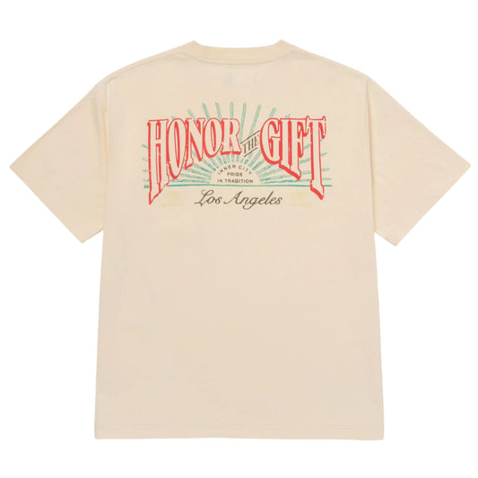 The Honor The Gift HTG Cigar Label SS Tee Bone, from the brand HONOR THE GIFT, is a vintage-style t-shirt crafted from 100% cotton. It features a beige color with "HONOR THE GIFT" in bold red lettering and "Los Angeles" in gray beneath it. The design is further enhanced with a sunburst pattern reminiscent of classic cigar labels.