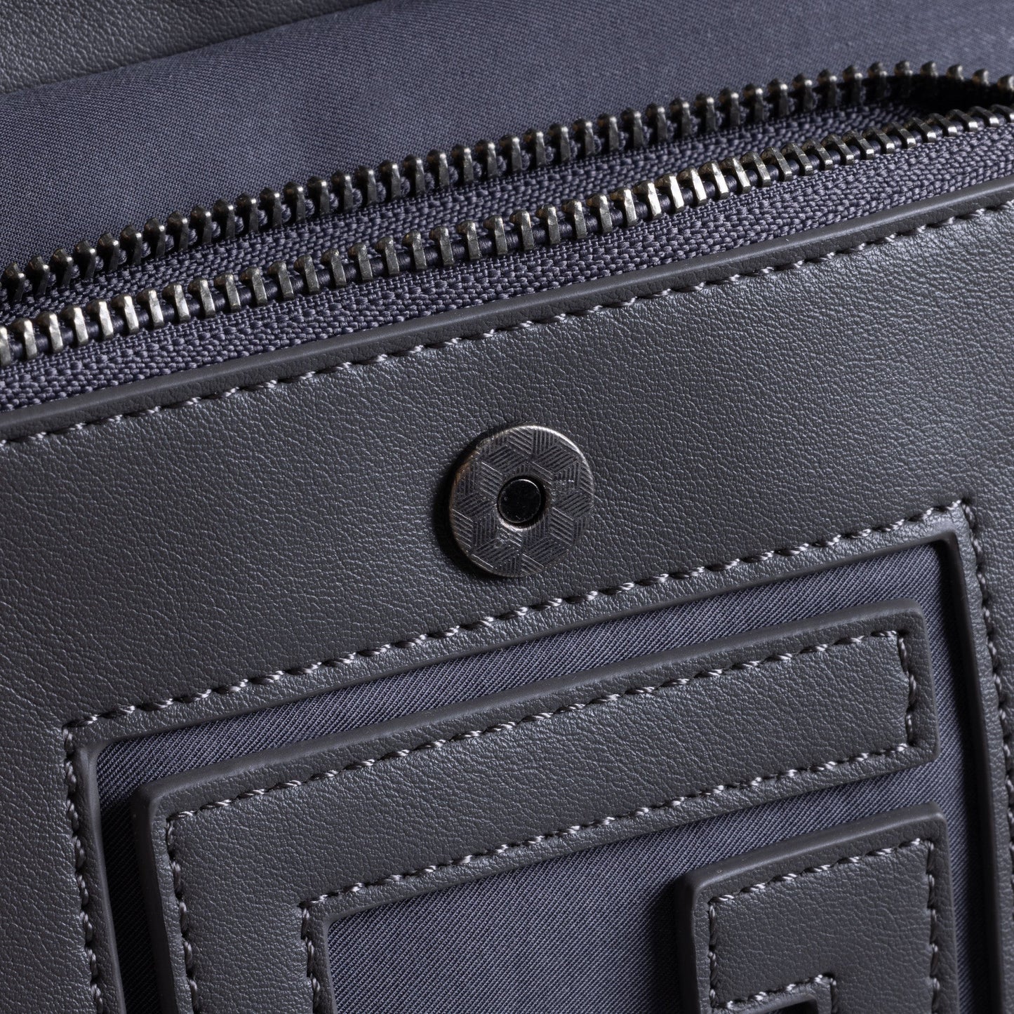 Close-up of the HONOR THE GIFT HTG SIDE BAG DARK GREY, featuring visible stitching, a zippered pocket, and an "H" logo circular snap button.