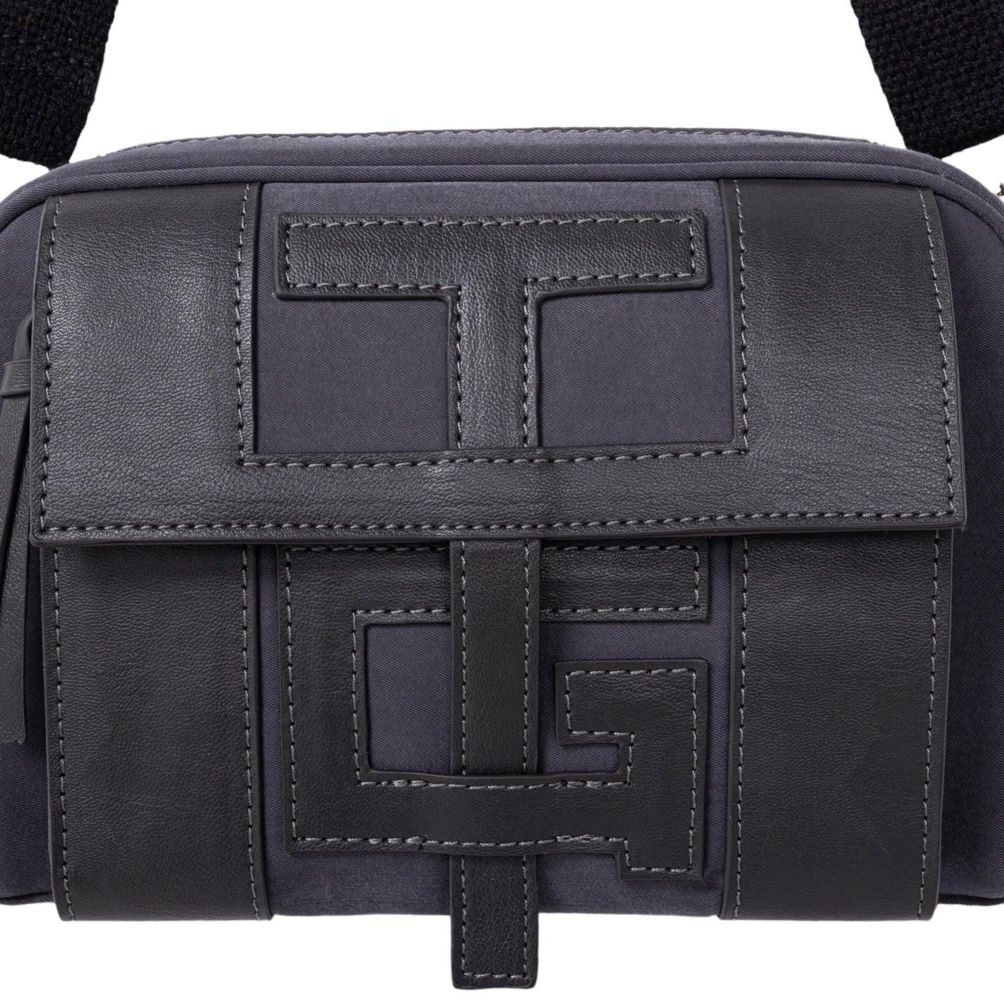 Close-up of the HONOR THE GIFT HTG Side Bag in dark grey, featuring an embossed geometric "H" logo closure on the front flap.