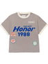 The HONOR THE GIFT Multi Box Tee Stone is a gray short-sleeve heavyweight cotton t-shirt with white trim, blue "THE GIFT Honor 1988" text, and colorful embroidered patches on the front for lasting style.