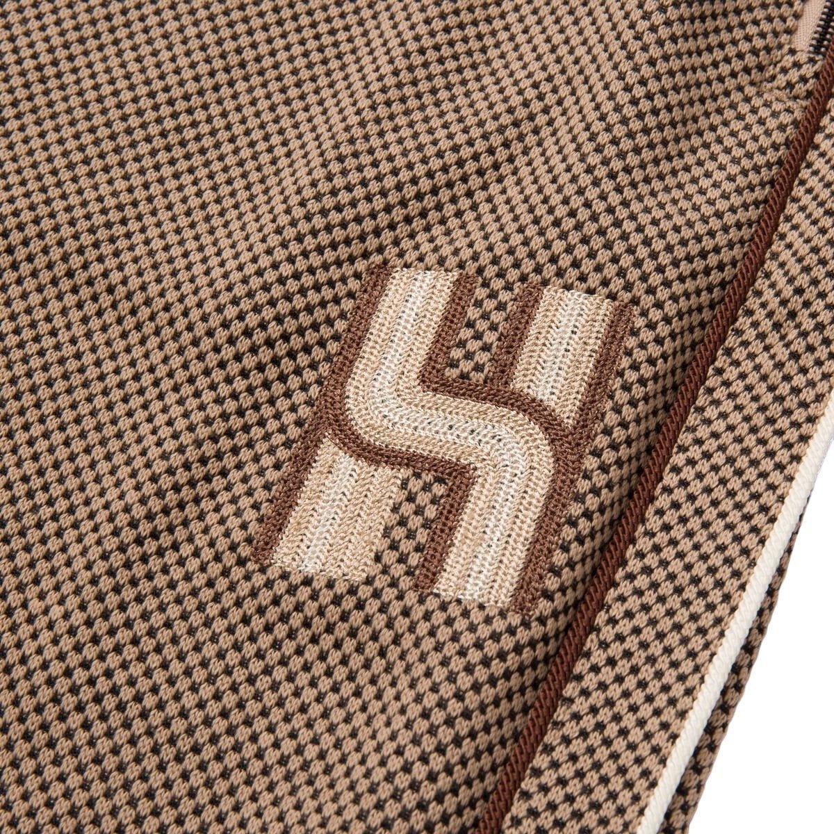 Close-up of the textured brown and beige checkered pique knit fabric featuring a stylized letter "H" design in white and brown, ideal for the HONOR THE GIFT Novelty Knit Track Pant Brown.