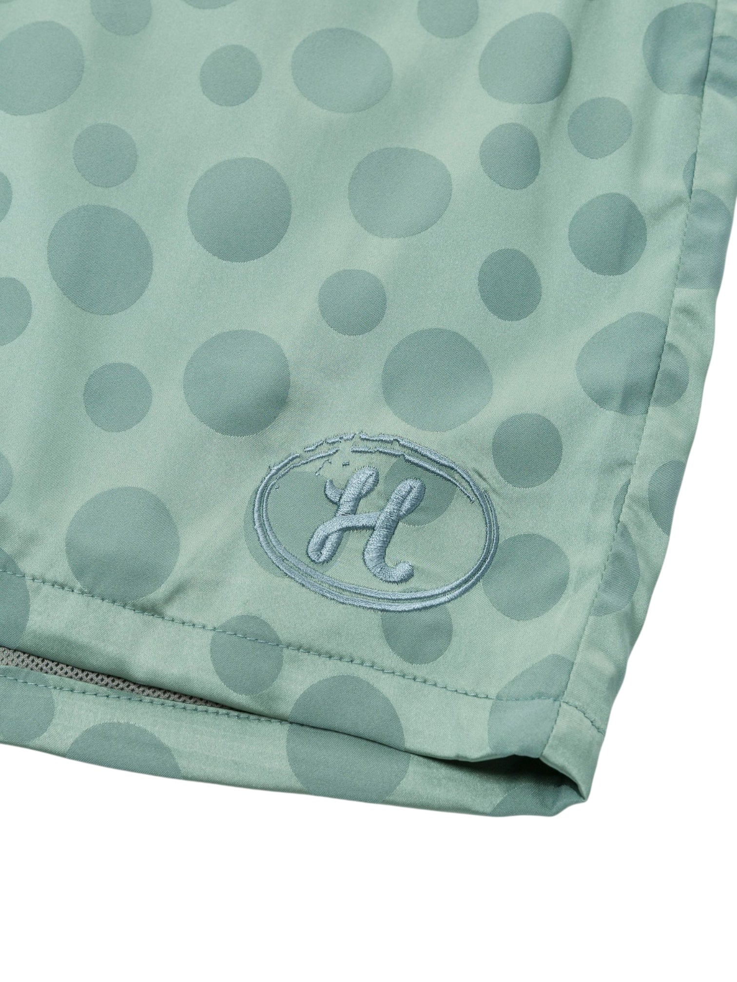 The HONOR THE GIFT Poka Dot Short Green features a light green polyester jacquard fabric with large polka dots, an embroidered "H" in an oval by the hem, and an adjustable drawstring for a perfect fit.