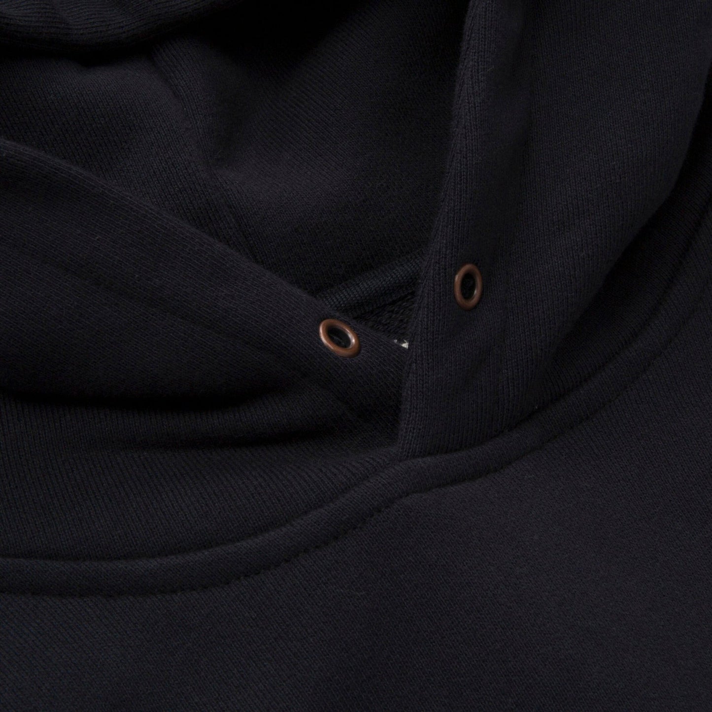 Close-up of the Honor The Gift Studio Hoodie Black by HONOR THE GIFT, a heavyweight terry hoodie in classic black. It features a drawstring hood with metal eyelets and boasts a bold puff print design that evokes inner city sounds.