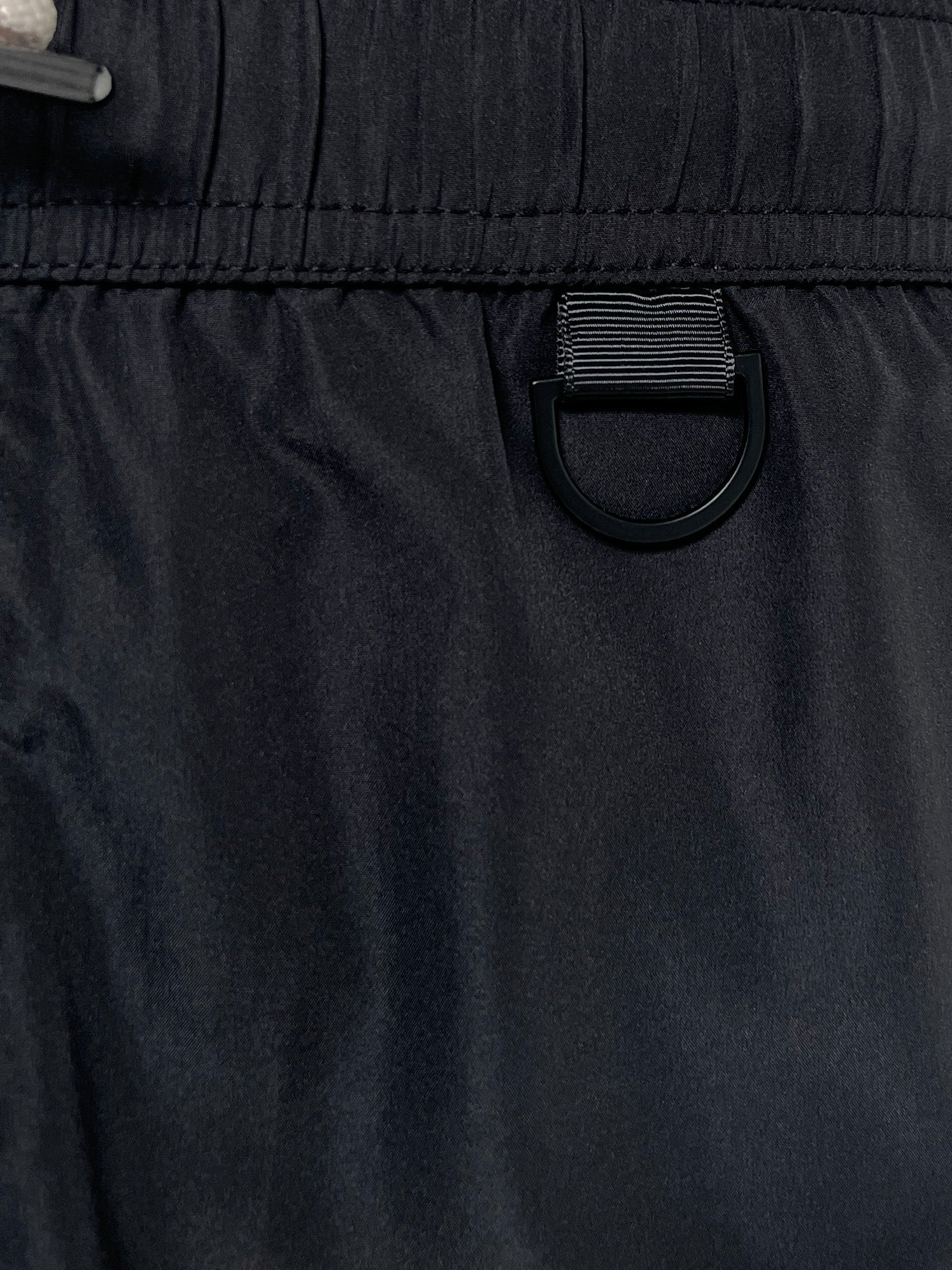 Close-up of ICEBERG ICE25MBM01 Medium Boardshort Black, crafted from black polyester with an elastic waistband and a black D-ring detail below the waist, inspired by classic Iceberg swim trunk styles.