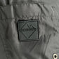 Close-up of the Iceberg ICE25MBM01 Medium Boardshort in black by ICEBERG, featuring a square patch with a stylized mountain and "ICEBERG" logo, plus a metal snap button detail on the lower right.
